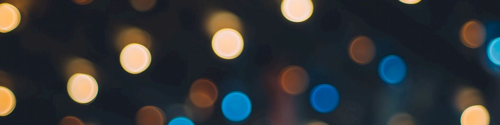 The image shows an out-of-focus view with multicolored bokeh lights against a dark background, creating a soft, abstract pattern.