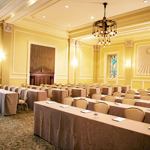 The image shows an elegant conference room with rows of tables and chairs, soft lighting, and decorative walls ending the sentence.