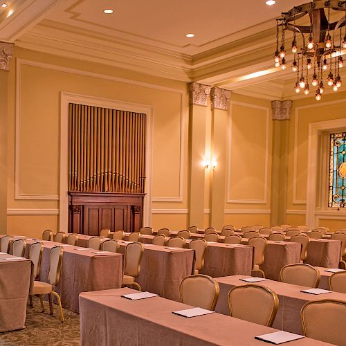 The image shows an elegantly decorated conference room with rows of tables and chairs, and a chandelier hanging from the ceiling, ending the sentence.