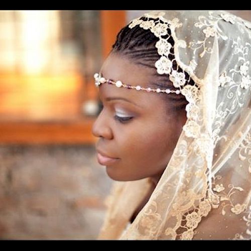 A woman in profile wears a lace veil with a floral headpiece, appearing serene and elegant.